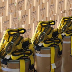 Barrels topped with neatly coiled yellow car tie-down straps with D-rings in front of stacked SBIA cardboard boxes.