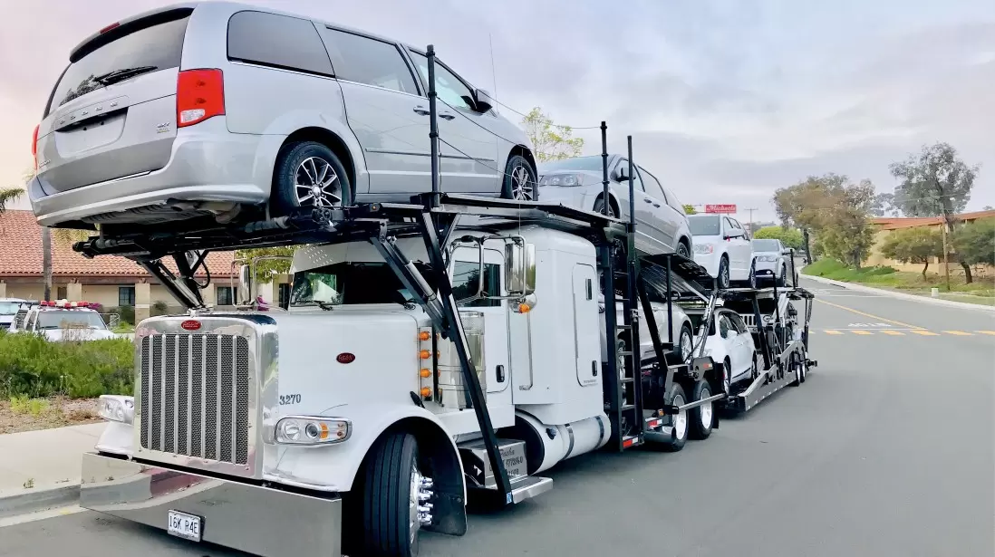 White car hauler semi transporting multiple vehicles on multi-level trailer